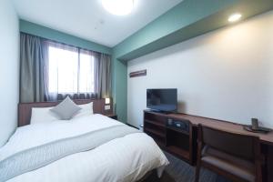 东京明神之汤神田尊贵多尔米酒店的一间卧室配有一张床和一张书桌及电视