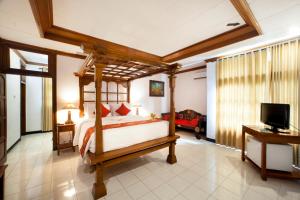 罗威那巴厘岛塔曼海滩及Spa罗维纳度假酒店的一间卧室配有一张天蓬床和一台电视机