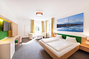 沃尔特湖畔佩莎赫Strandhotel Kärntnerhof的一间卧室配有一张床、一张书桌和一台电视。