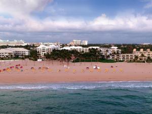 劳德代尔堡拉戈马尔海滩度假俱乐部酒店的海滩上设有椅子和遮阳伞,还有建筑
