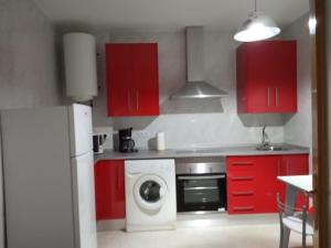 特鲁希略Apartamento Turistico La Victoria的一间带红色橱柜和洗衣机的厨房