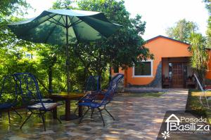 恩卡纳西翁Posada Basiliza, Encarnación PY的庭院内桌椅和遮阳伞