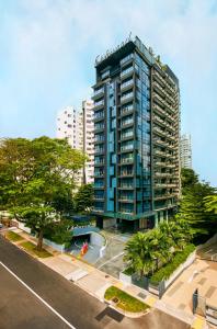 新加坡Oakwood Studios Singapore的一座高大的蓝色建筑,前面有树木