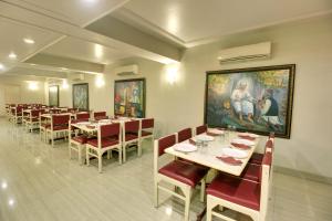 舍地Hotel Sai leela - Shirdi的一间带桌椅的用餐室和一幅画