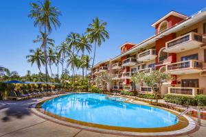 巴加Lazy Lagoon, Baga A Lemon Tree Resort, Goa的棕榈树建筑前的游泳池