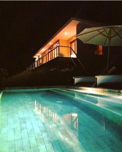 龙目岛库塔Villa Atas Pelangi的一座大型游泳池,在晚上在房子前面