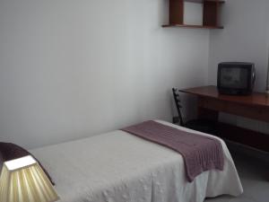 卢戈彭特维拉旅馆的一间卧室配有一张床、一张书桌和一台电视