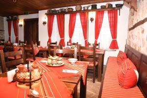 帕纳久里什泰尤杰瓦凯施塔酒店的用餐室配有木桌和红色窗帘