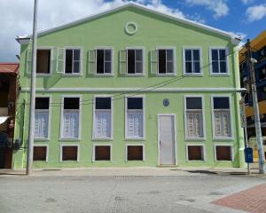 萨尔瓦多Mar à Vista Hostel的街道上白色百叶窗的绿色建筑