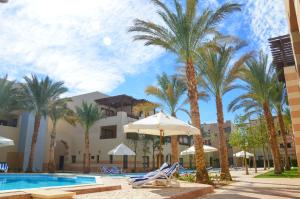 加利布港Port Ghalib Marina Residence Suites的棕榈树和椅子的度假村和游泳池