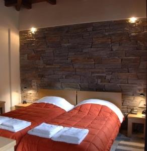 卡兰巴卡Thalia Rooms的一间卧室配有一张红床和砖墙