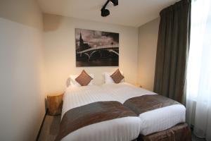 列日Amosa Liège City Centre Apart Regence 17的卧室配有一张白色床,墙上挂有绘画作品