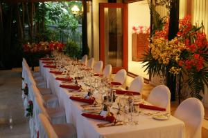 劳托卡斐济兰花度假村的一张长桌子,上面有白色的桌子和椅子,花卉