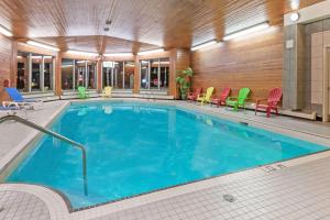 Stony PlainStony Plain Inn & Suites的酒店客房的大型游泳池配有五颜六色的椅子