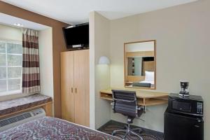 夏洛特大学广场温德姆酒店的酒店客房配有书桌、床和镜子