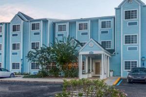 夏洛特港Microtel Inn & Suites by Wyndham Port Charlotte Punta Gorda的蓝色的建筑,前面有停车位