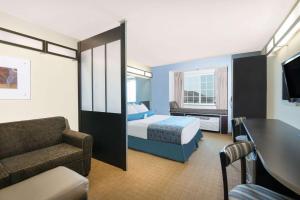 StanleyMicrotel Inn & Suites by Wyndham Stanley的酒店客房配有床、沙发和椅子