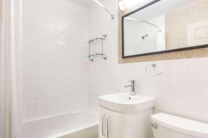 金斯顿Howard Johnson Inn by Wyndham Kingston的白色的浴室设有水槽和镜子
