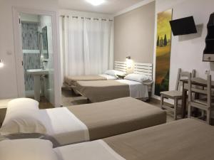 莫特里尔Hostal Puerto Beach的酒店客房带四张床和一张桌子以及椅子。