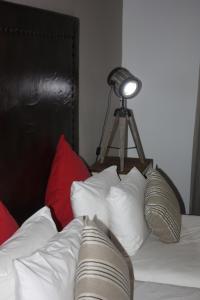 奥奇瓦龙戈布什枕头旅馆的一张带白色枕头的床和一张带灯的三角架