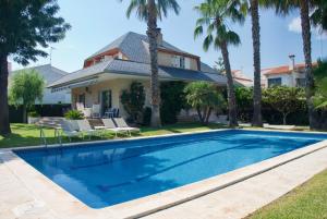 托里代巴拉Villa Cala de la Mora的棕榈树屋前的游泳池