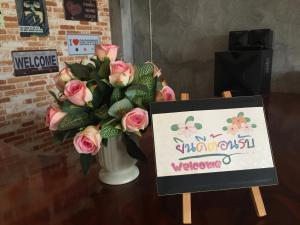 素叻You In House URT Surathani Airport的粉红色玫瑰花瓶,带有迎宾标志