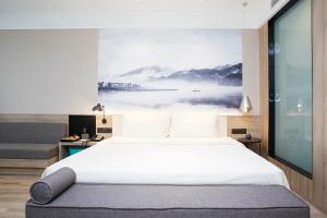 杭州杭州金沙湖亚朵酒店的卧室配有一张大床,墙上挂有绘画作品