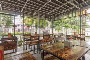 美娜多RedDoorz at Jalan Babepalar Rike Manado的餐厅设有木桌、椅子和窗户。