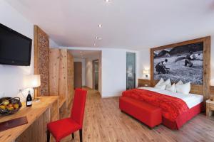 布鲁尼科阿玛腾酒店的一间卧室配有一张大床和一张红色椅子