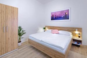 布拉格DownTown Suites Jugoslavska的一间卧室配有一张带白色床单和木制橱柜的床。