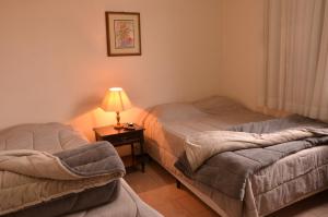 圣若阿金Hotel Maristela的一张桌子上灯的房间里两张床铺