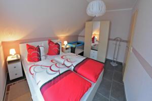 马林费尔德Ferienhaus Müritzidyll / OG-Appartement的卧室配有红色和白色的床和镜子
