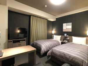 古河市古贺站前路特酒店的酒店客房设有两张床和一台平面电视。