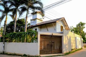 科伦坡Eden Studio Apartments - 1的一座白色的房子,设有车库和棕榈树