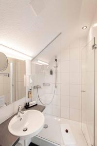 苏黎世雷克斯速乐酒店的白色的浴室设有水槽和淋浴。