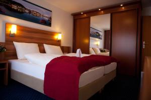 乌尔丁根-米赫尔霍芬港口可努斯酒店的一间卧室配有一张带红色毯子的大床