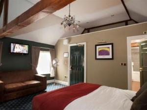 纽伯里威瑟斯本哈奇特酒店的一间卧室配有一张床、一张沙发和一台电视。