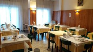 西尼加利亚Albergo Moretti的餐厅设有白色的桌子和绿色的椅子