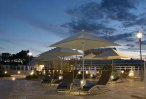 滨海波利尼亚诺Vilu Suite Mare的一群晚上的椅子和遮阳伞