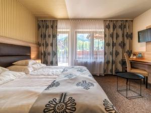 扎科帕内Hotel Zakopane Wellness & SPA ex Korona Tatr的配有一张床、一张书桌和一扇窗户的酒店客房