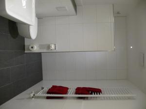 SalzkottenGästehaus Fraune的白色瓷砖浴室,在架子上配有2条红色毛巾