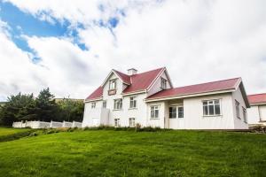 TjörnÓsar Hostel的绿色田野上红色屋顶的白色房子