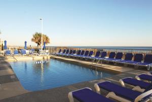 默特尔比奇Seaside Resort by Capital Vacations的一个带椅子的游泳池,背景是大海