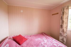 芬斯内斯Midt Troms Perle的卧室配有粉红色的床和红色枕头