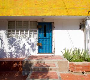 巴兰基亚QuillaHost Tropical Apartment的黄色屋顶房子上的一扇蓝色门