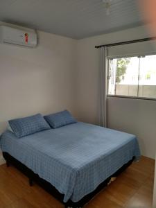 巴拉奈里奥-坎布里乌Quitinete Balneário的一间卧室配有一张带蓝色床单的床和一扇窗户。
