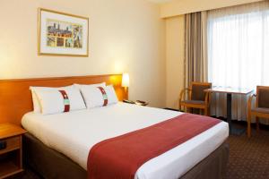 根特根特展会假日酒店的酒店客房设有一张大床和一张桌子。