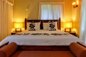 拉罗汤加特阿瓦海滩度假屋的一间卧室配有一张大床和两盏灯