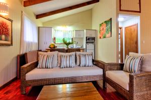 拉罗汤加特阿瓦海滩度假屋的一间带两张柳条沙发的客厅和一间厨房