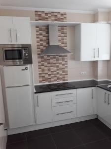 安特克拉Ático céntrico的白色的厨房配有白色的橱柜和微波炉